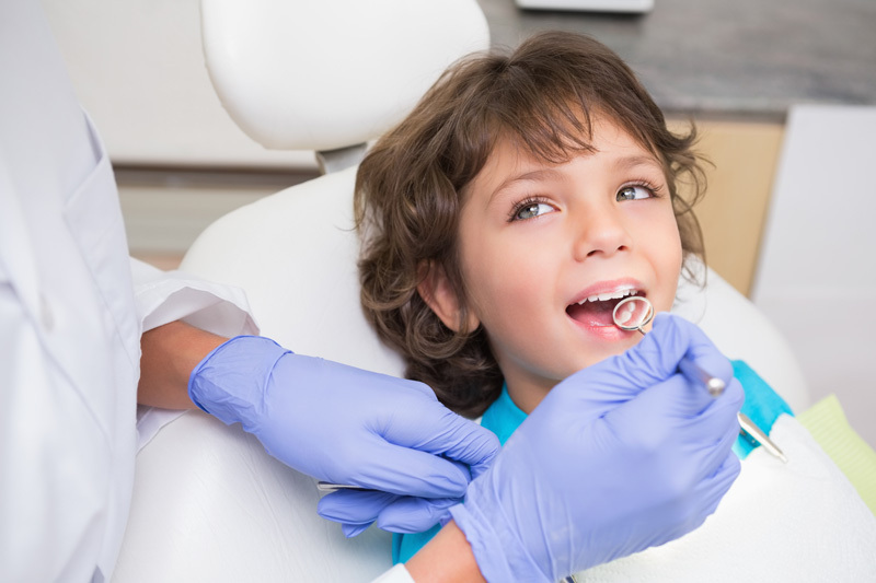 pediatric dentist examining little boys teeth in the dentists chair