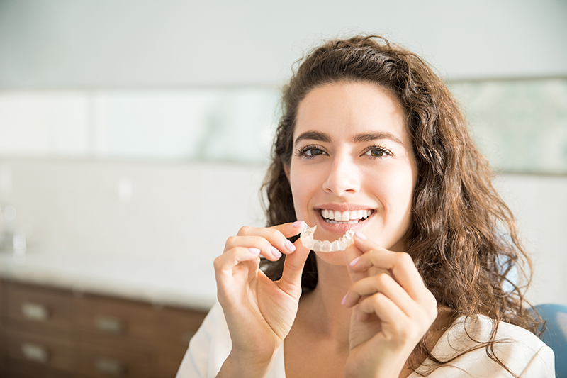 retrato hermosa paciente sosteniendo retenedores ortodoncia clinica dental 1
