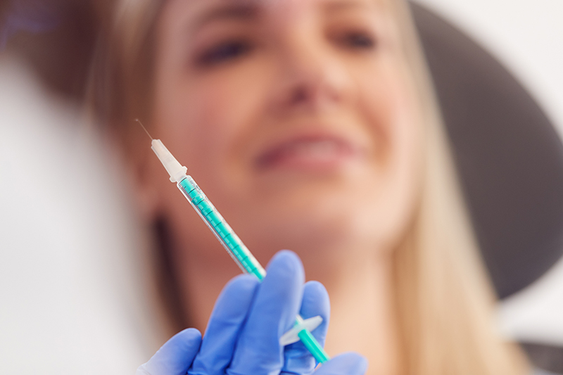 Médico que prepara al paciente para la inyección de neuromoduladores