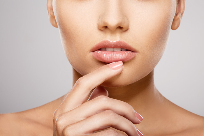 mujer tocándose los labios con su dedo índice levemente apoyado sobre su labio inferior